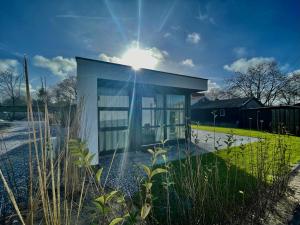 een klein gebouw met de zon er achter bij Edelhert, moderne en comfortabele vakantiewoning met hottub! in Ermelo