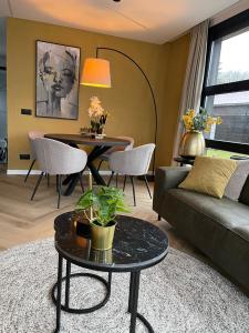 - un salon avec un canapé et une table dans l'établissement Edelhert, moderne en comfortabele vakantiewoning met hottub!, à Ermelo