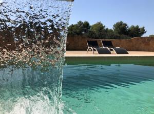 two chairs and a fountain in front of a pool at Agroturisme Son Samà in Llucmajor +46 photos