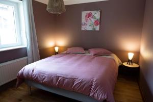 een slaapkamer met een bed met roze lakens en 2 lampen bij Gîte de l'Abeille 