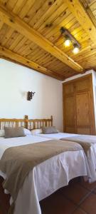 two beds in a room with wooden ceilings at Hostal Restaurante Serrania in Tragacete