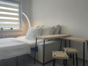 ein Schlafzimmer mit einem Bett und zwei Tischen neben einem Fenster in der Unterkunft Apartman na kopci in Košice