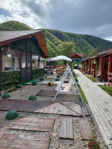 einen Garten mit einem Holzsteg neben einem Gebäude in der Unterkunft Clisura Dunarii Casutele Danca in Ogradena