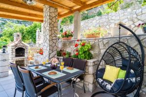 eine Terrasse mit einem Tisch, Stühlen und einer Steinmauer in der Unterkunft Lovely studio apartment in Sobra