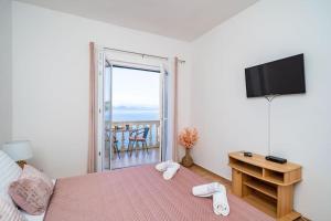 Schlafzimmer mit einem Bett, einem TV und einem Balkon in der Unterkunft Lovely studio apartment in Sobra