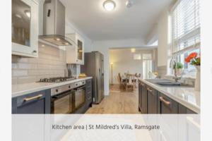 eine Küche mit blauen Schränken und eine Küche mit einem Esszimmer in der Unterkunft St Mildreds Villa, Ramsgate Royal Harbour, Kent in Ramsgate