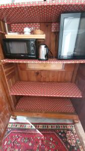 an interior view of a kitchen with two shelves and a microwave at Une Suite au jardin in Orval