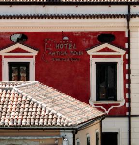 czerwony budynek z dwoma oknami i znakiem na nim w obiekcie Antichi Feudi Dimora D'Epoca w mieście Teggiano