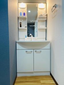 a bathroom with a white sink and a mirror at Namba Shinsaibashi 10 mins Reiko guest house in Osaka