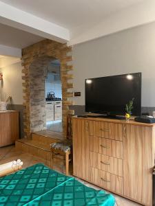 a living room with a flat screen tv on a wooden cabinet at agroturystyka Pensjonat PAULA in Muszyna