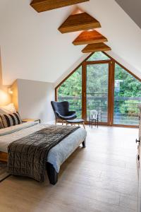 a bedroom with a bed and a chair and a window at Mielno 77 Dom wakacyjny na Mazurach in Mielno