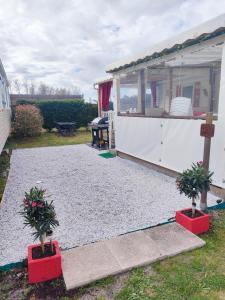 un remolque blanco con dos macetas delante de él en Mobil home climatisé au Domaine Lalande à Mimizan, en Mimizan