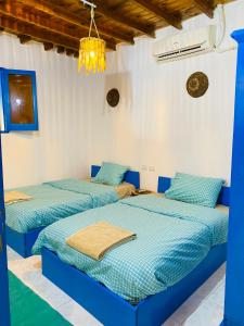 2 letti in una camera con pareti bianche e blu di Blue House in Lighthouse a Dahab