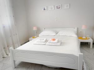 1 cama blanca con 2 toallas y 2 mesas en Fairy home Porto Heli en Porto Heli