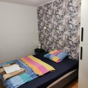 een kleine slaapkamer met een bed met kleurrijke kussens bij Dom wczasowy Maja in Dźwirzyno