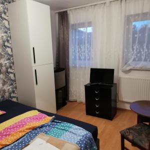 um quarto com uma cama e uma televisão numa cómoda em Dom wczasowy Maja em Dźwirzyno