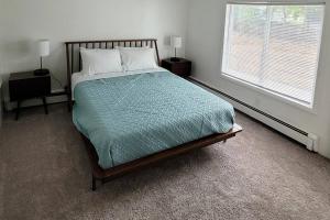 a bedroom with a bed with a green comforter and a window at Waterfront Cottage near Lambeau and Door County! in Green Bay