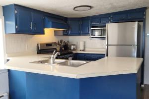 a kitchen with blue cabinets and a stainless steel refrigerator at Waterfront Cottage near Lambeau and Door County! in Green Bay