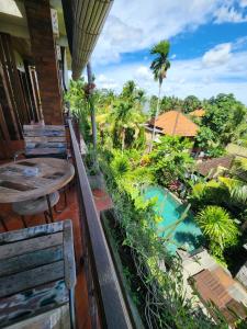 balcón con vistas a la piscina y a las palmeras en BUDA AMITABA en Ubud