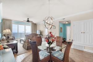 uma sala de estar com uma mesa de vidro e cadeiras em Emerald Isle 1201 em Panama City Beach