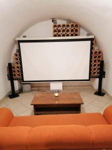 a large screen in a room with a couch and a table at Parraghegy Apartman in Zalaszántó