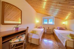 Zimmer mit 2 Betten, einem Tisch und einem Spiegel in der Unterkunft Apartment Lipovac in Malinska