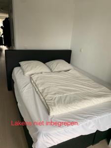 een bed met witte lakens en kussens in een kamer bij Nieuwbouwappartement Lippenslaan, 2 -Slaapkamers in Knokke-Heist