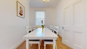 a white dining room with a white table and chairs at Cheerful 4 Bedroom Victorian house with back courtyard in London