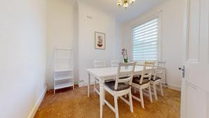 a white dining room with a white table and chairs at Cheerful 4 Bedroom Victorian house with back courtyard in London