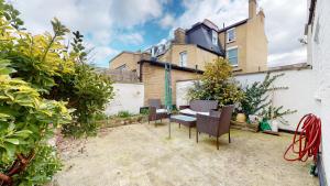 a garden with chairs and a table in front of a house at Cheerful 4 Bedroom Victorian house with back courtyard in London