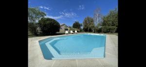 una gran piscina azul con 2 sillas blancas en Spacious & Characterful 6 Bed Farmhouse with Pool en Vanzay