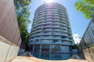 a tall white apartment building with a pool in front of it at Modern condo in Nimman with panoramic city view in Chiang Mai