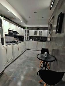eine Küche mit weißen Schränken sowie einem Tisch und Stühlen in der Unterkunft شقه راقيه بتصميم مختلف in Tabuk
