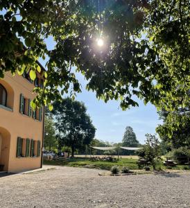 a building with the sun shining through a tree at Cascina Bagaggera in Rovagnate