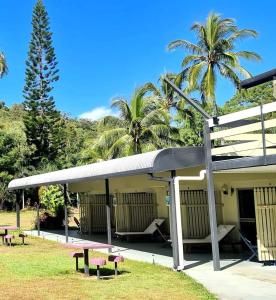 a building with a picnic table and palm trees at Bramston beach resort in Bramston Beach