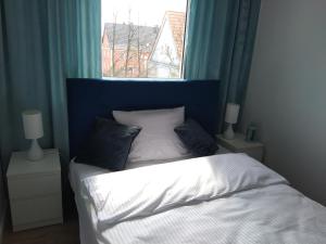 a bed with a blue headboard and a window at Tabago Studio 7 in Kędzierzyn-Koźle