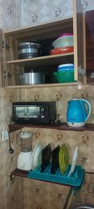 une étagère de cuisine avec de la vaisselle et un four micro-ondes dans l'établissement Cozy Sitting-room and Bedroom, à Lekki