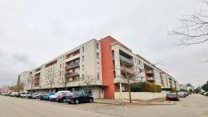 duży budynek z samochodami zaparkowanymi na parkingu w obiekcie Le SMART - Parking - Terrasse - Wifi - Mulhouse - Relax BNB w mieście Pfastatt
