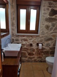 Baño de piedra con lavabo y aseo en Casa Andrés Quilmas, en Carnota