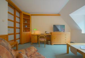 a living room with a couch and a desk with a television at Hotel Praha in Hřensko