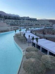 a swimming pool with straw umbrellas and a resort at Lagoon View 2 Bedroom IL Monte Galala Ain Sokhna C2-CH28-2-1 in Ain Sokhna