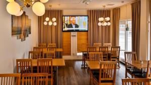 um restaurante com mesas e cadeiras de madeira e uma televisão em Hotel Amadeus em Halmstad