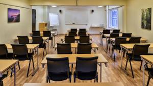 uma sala de aula com mesas e cadeiras e um quadro branco em Hotel Amadeus em Halmstad