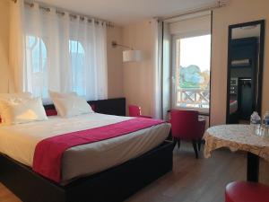 Schlafzimmer mit einem Bett, einem Tisch und einem Fenster in der Unterkunft Logis Hôtel Saint Guirec Et De La Plage in Perros-Guirec