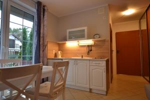 a kitchen with a table and a sink and a window at Apartamenty Poddąbie z ogródkiem in Poddąbie