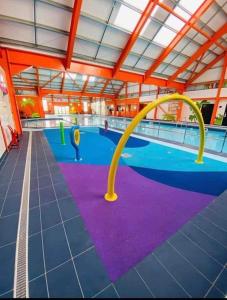 una grande piscina con attrezzature viola e gialle di Avonmore Martello Beach a Clacton-on-Sea