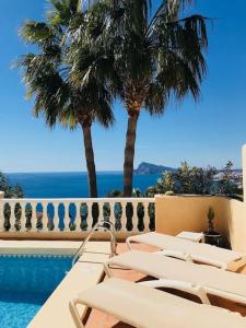 um grupo de cadeiras sentadas ao lado de uma piscina em VILLA ALTEA HILLS, vue mer, piscine chauffée, WIFI em Alicante