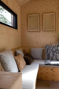 a couch in the corner of a tiny house at Vague Luxurious Tiny House Luxe Wellness, Spa Bad,Beamer, Veluwe in Nunspeet