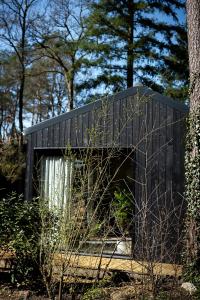 a black building sitting in the middle of a forest at Vague Luxurious Tiny House Luxe Wellness, Spa Bad,Beamer, Veluwe in Nunspeet