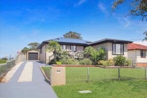 a large house with a gate and a driveway at Sunny Shores House with Private Pool in Lake Illawarra